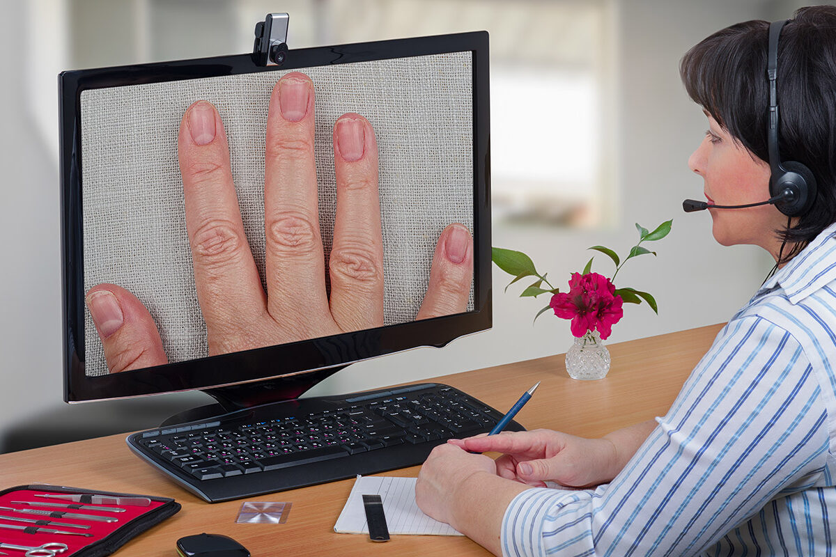 Telemedicine dermatologist looking fingernails Telemedicine female dermatologist in headset looks at peeling off nails layers of female patient on monitor with attention. Virtual doctor sees falling off fingernails either by online video chat or snapshot. Horizontal mid-shot on blurry indoors background